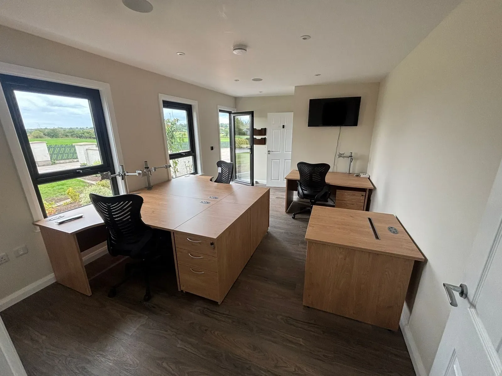 Garden office fitted out with desks, chairs and a TV